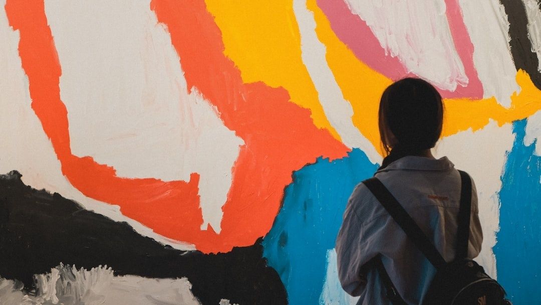 Personne observant une grande peinture abstraite aux couleurs vives