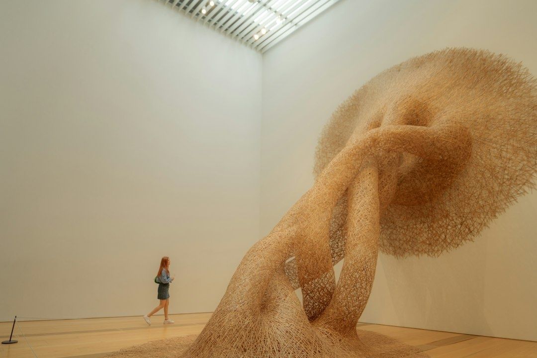 Installation monumentale en fibres végétales, observée par une visiteuse